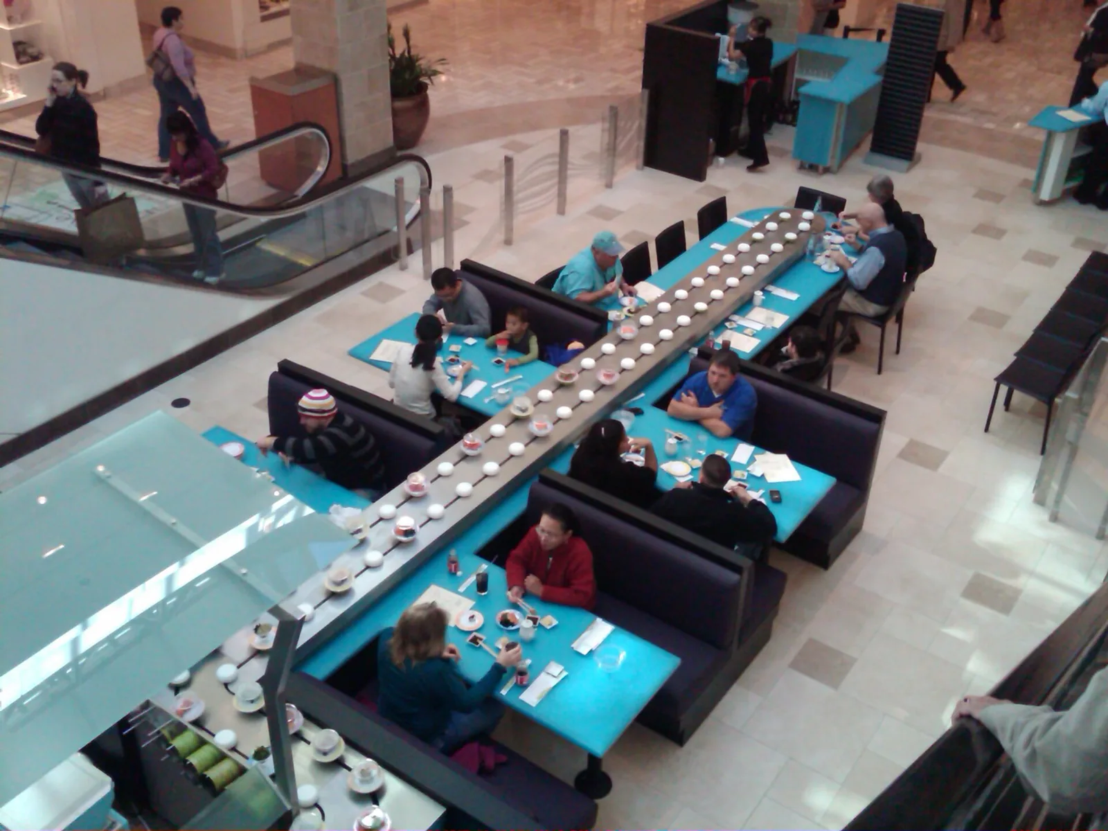 Plates of sushi on a long conveyor belt at a sushi bar