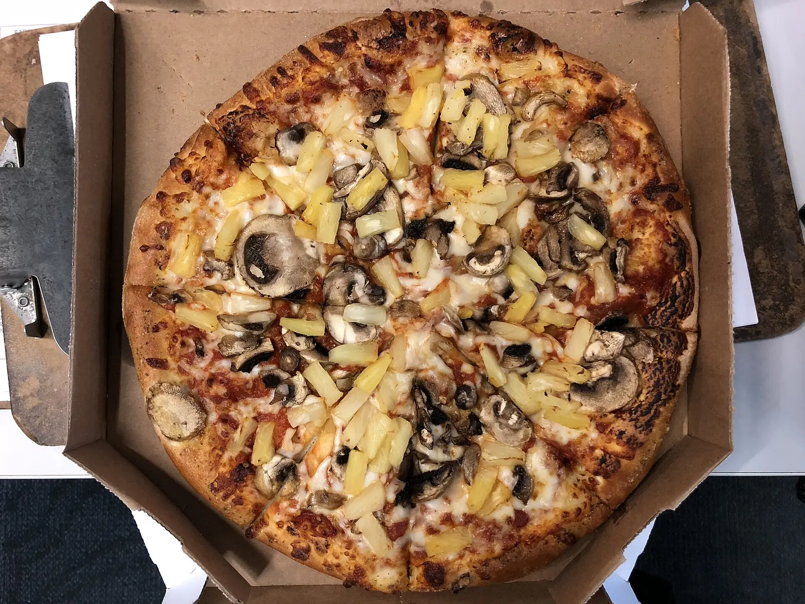 A delivery pizza topped with mushrooms and pineapple, photographed in Sterling, Virginia
